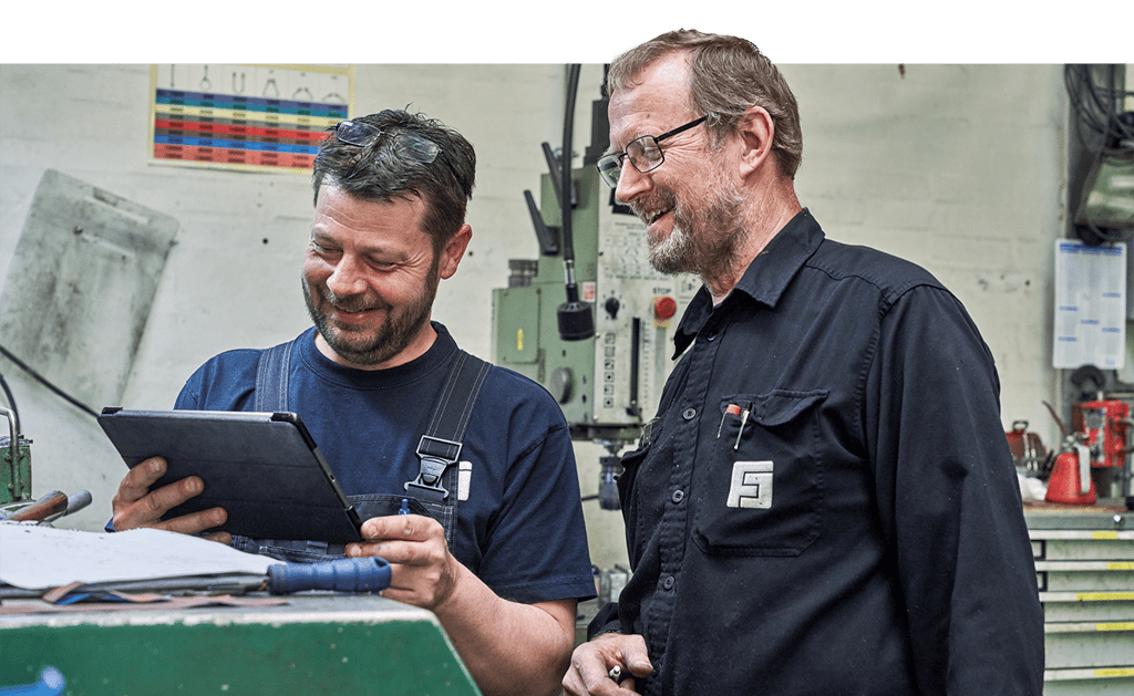 To håndværkere smiler mens de kigger ned på tablet